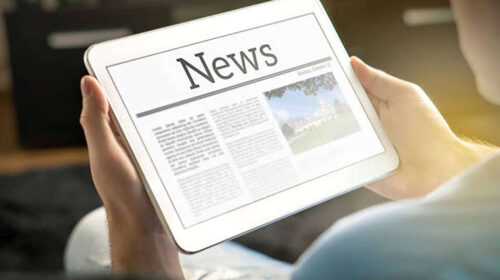 hands holding tablet with news page