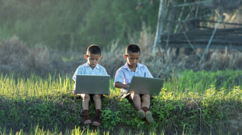 2 asian children with laptops in nature