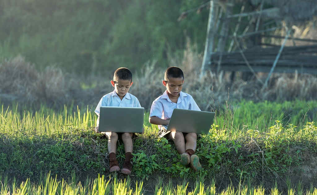 2 asian children with laptops in nature