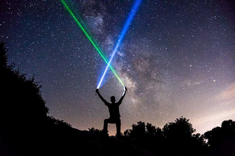 man holding 2 laser beam to the sky